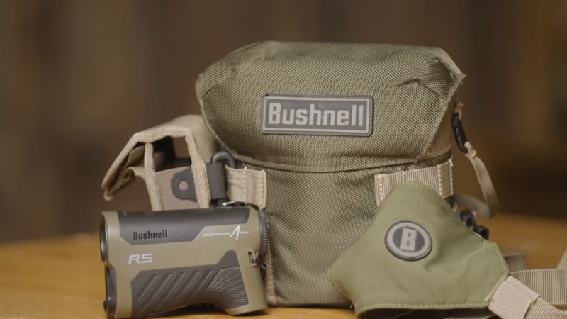 Bushnell R5 8×42 Binoculars with A Durable Green Carrying Case and Accessories Displayed on A Wooden Surface