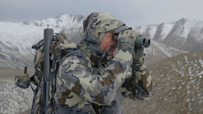 Hunter in Camouflage Gear Using Vortex Razor UHD 8×32 Binoculars in A Snowy Mountain Landscape