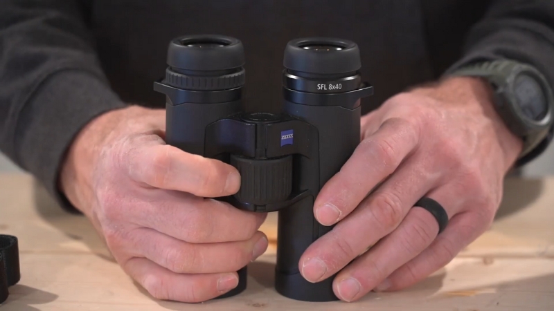 Close-Up of Hands Holding Zeiss SFL 8×40 Binoculars on A Wooden Surface