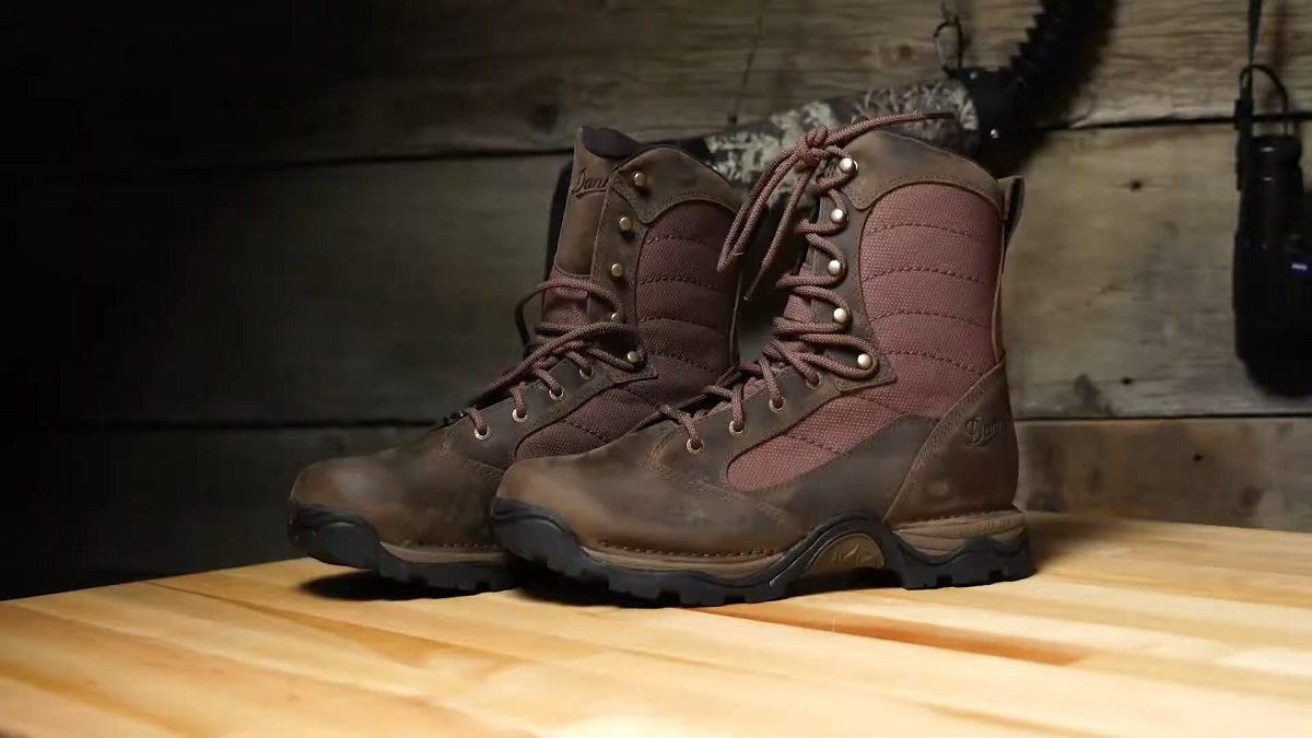 Durable brown boots with fabric paneling on a wooden surface