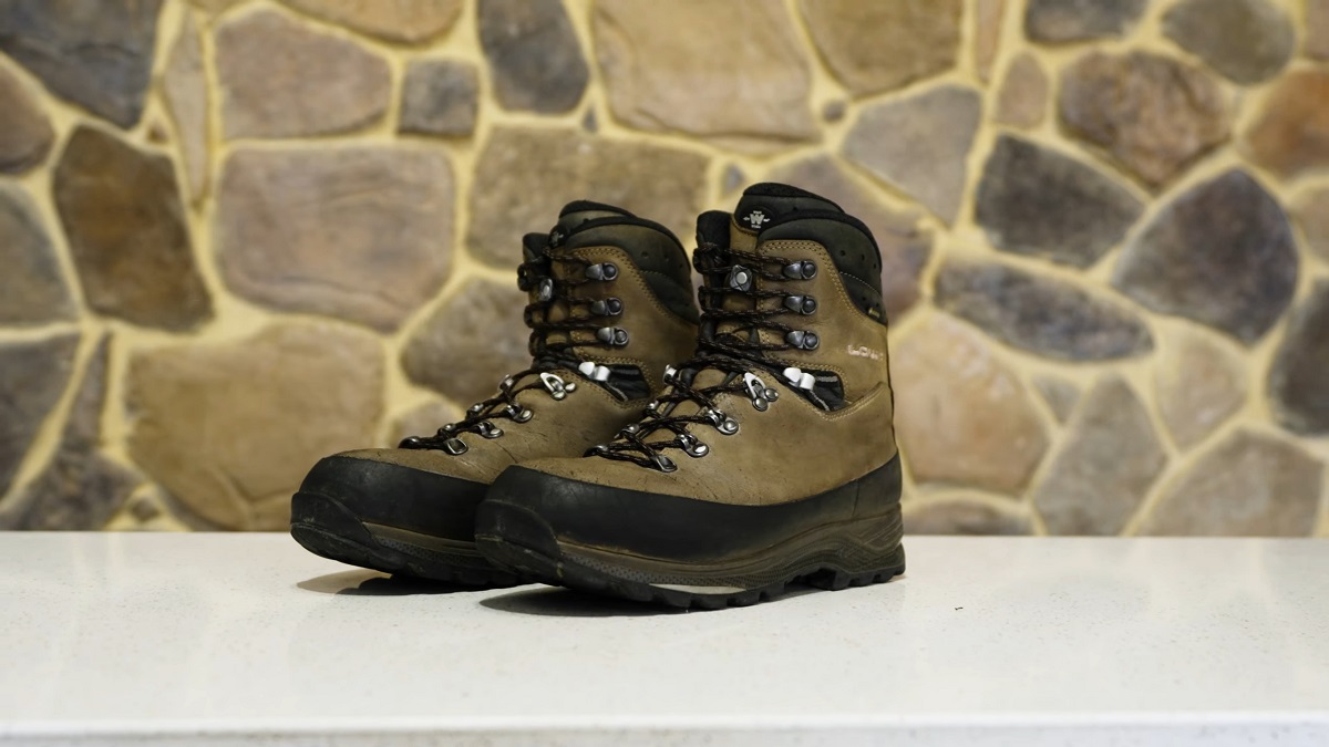 Pair of rugged black and brown hunting boots against a stone background