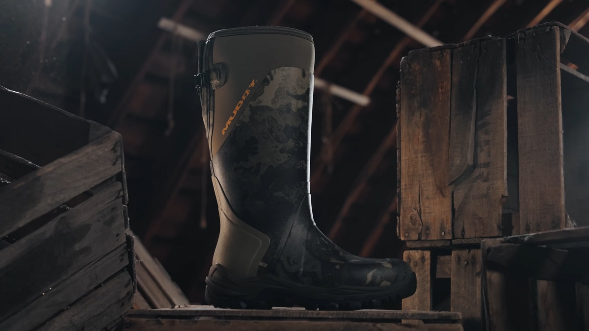 A single high-cut camo-patterned boot stands on a rustic wooden crate