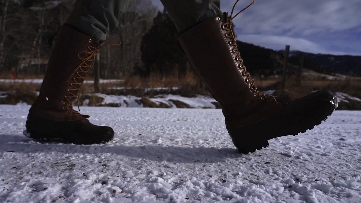 Close-up of insulated hunting boots walking on snowy terrain